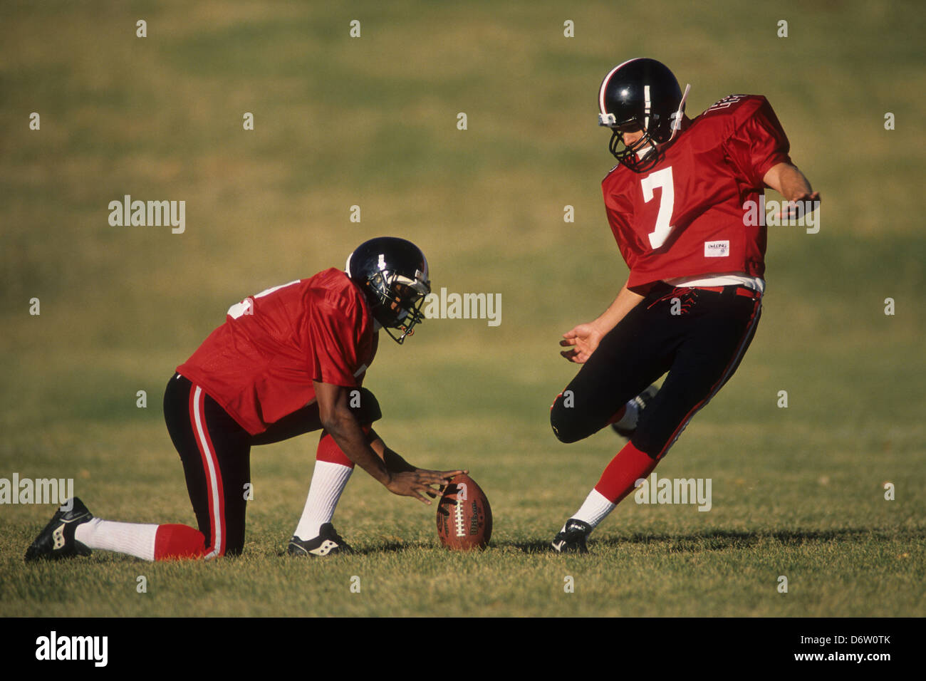 Football place kicker and holder in action., Stock Photo