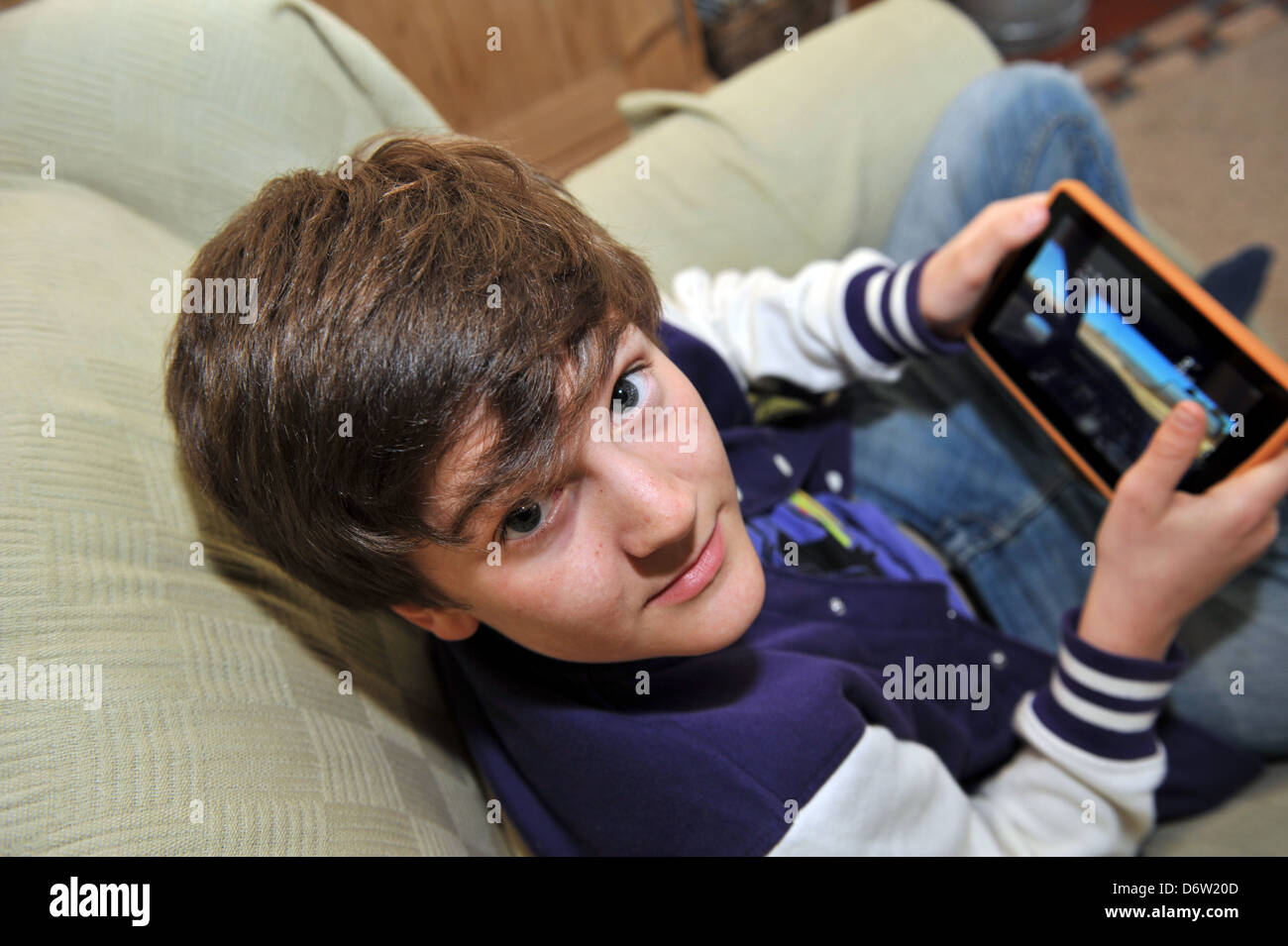 Twelve year old boy playing on a Kindle tablet. Stock Photo