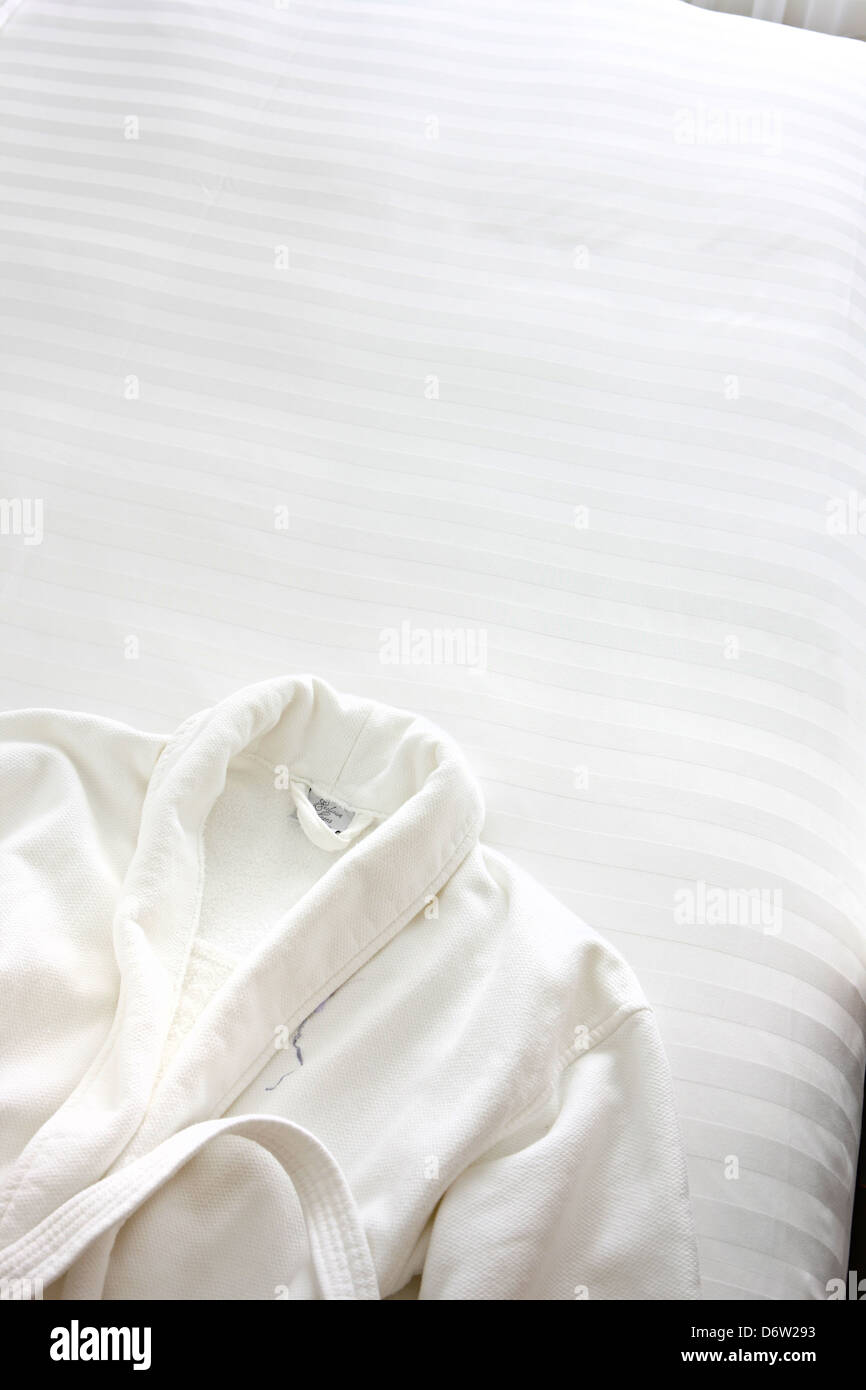 white dressing gown on white cotton bed Stock Photo
