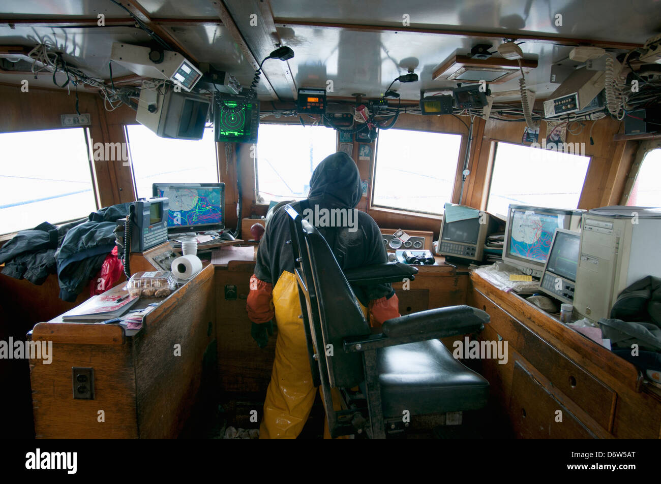 Captain at helm, checking computers and instruments for seagoing information, while dragging for Atlantic Cod (Gadus morhua) Stock Photo