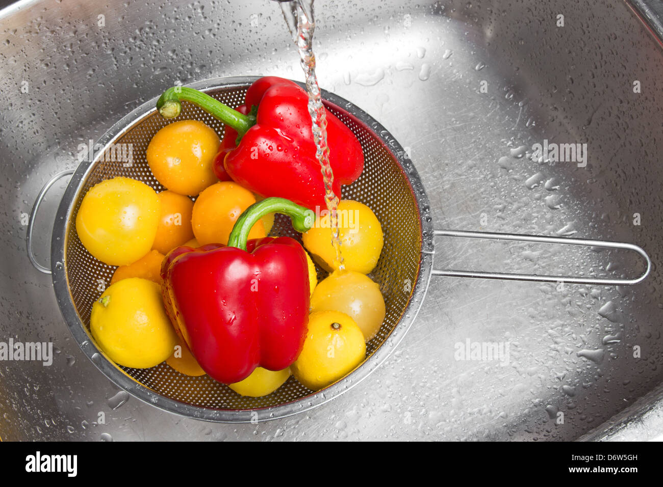 Washing colorful fruits and vegetables in the kitchen sink Stock Photo