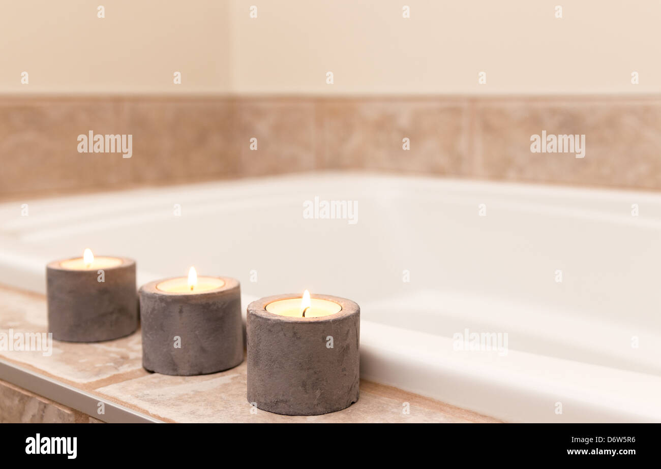 Three candles in concrete candle holders decorating bathroom Stock