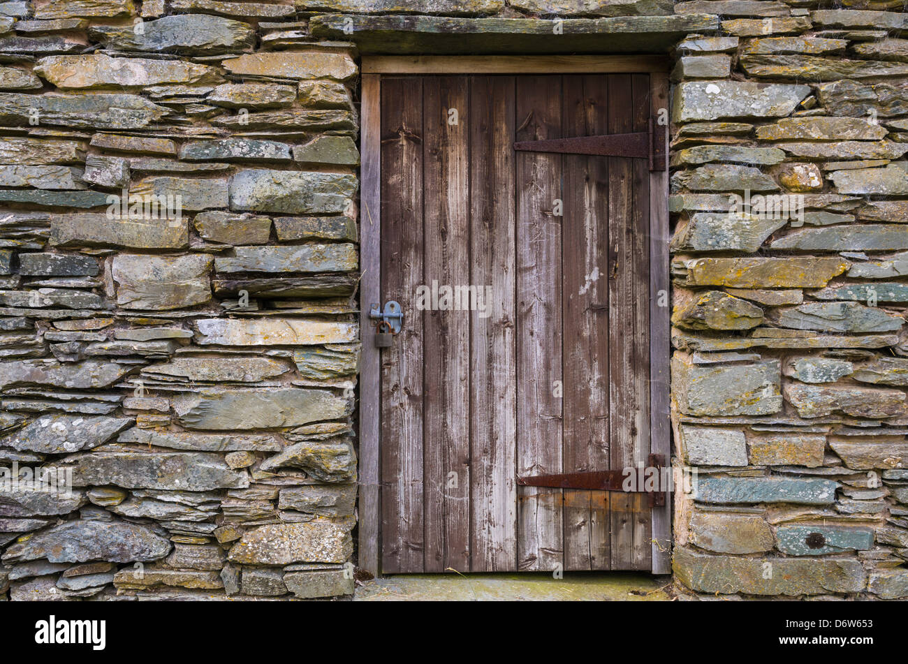 Locked wooden door on a stone outbuilding on a farm in the Lake District, Cumbria, England. Stock Photo
