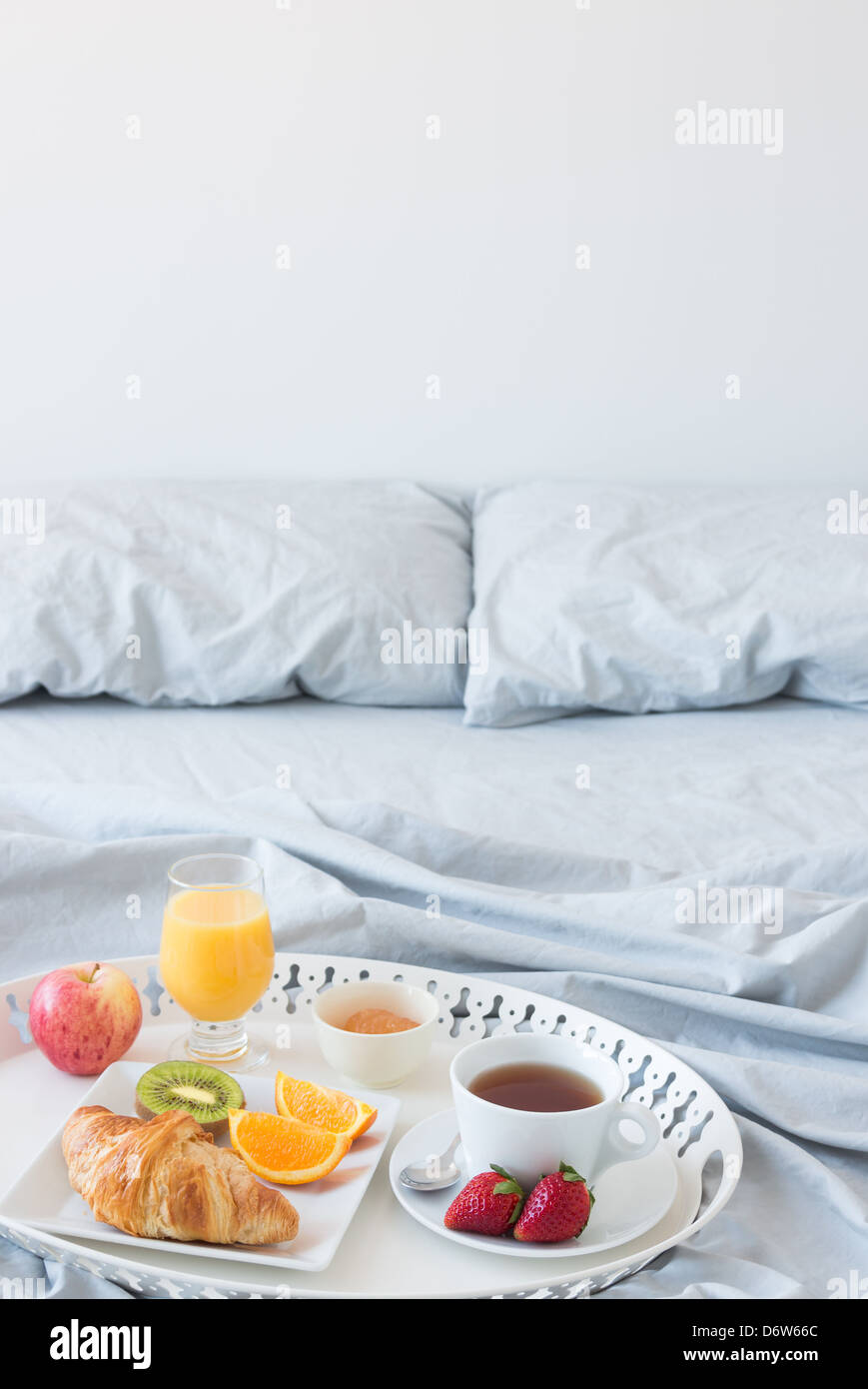 Tray with healthy breakfast on a bed with gray bed linen. Copy space. Stock Photo