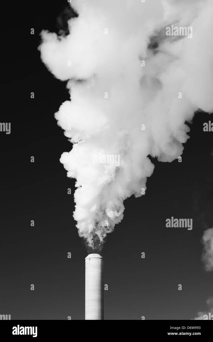 White steam rises out of a stack of a power plant Stock Photo
