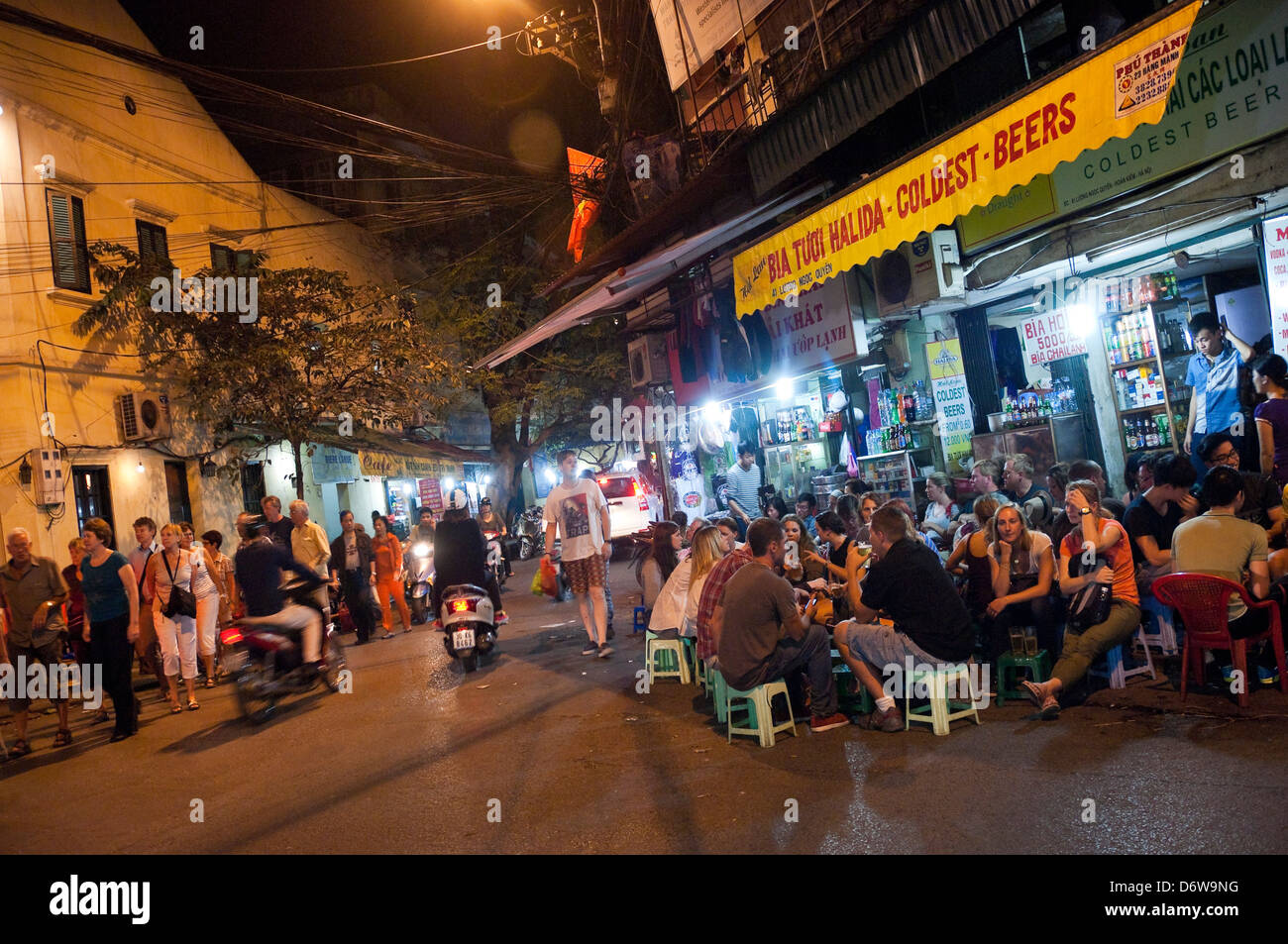 Horizontal wide angle of lots of tourists and locals drinking beer on the street in the Old Quarter in Hanoi at night. Stock Photo