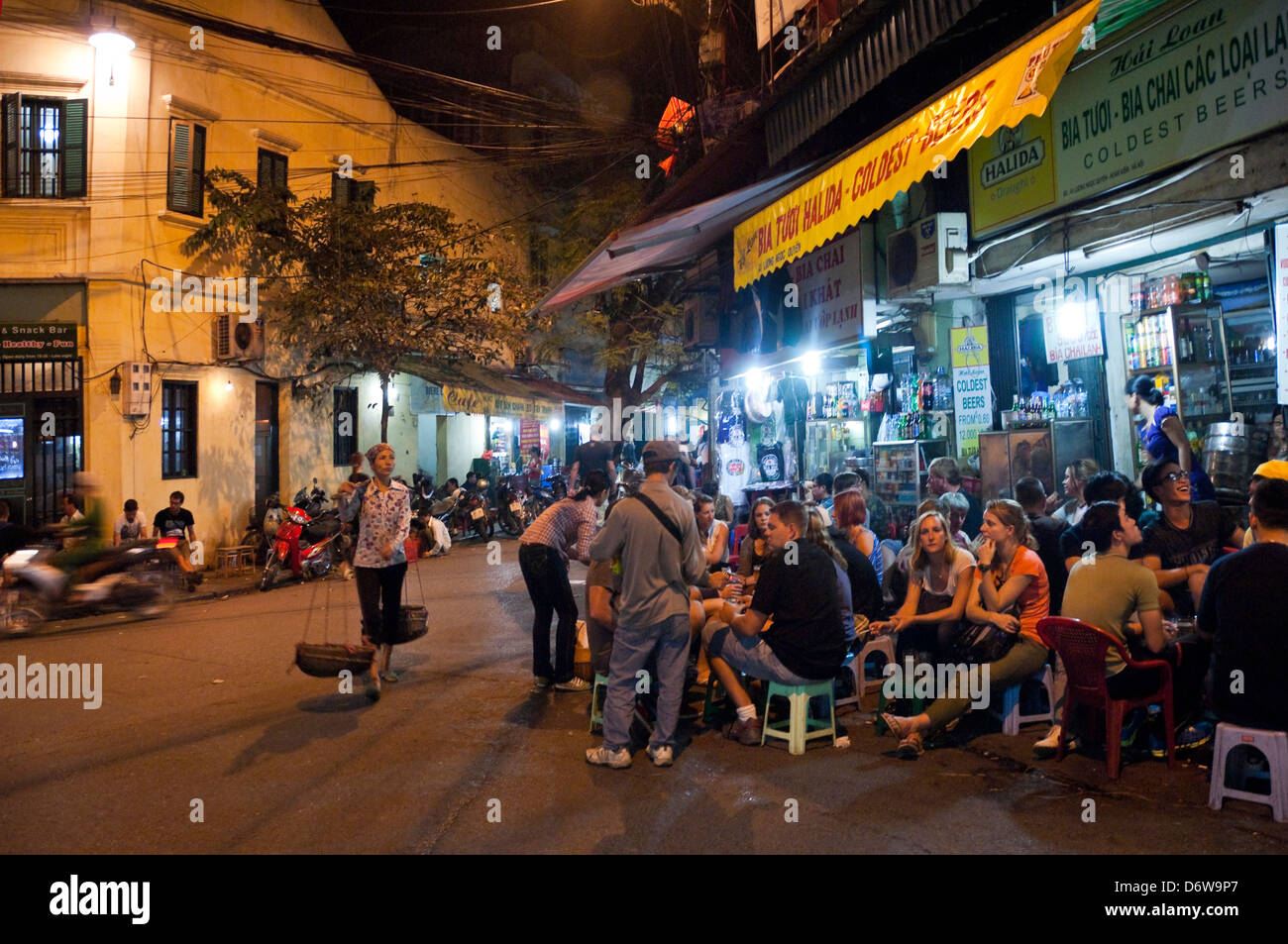 Horizontal wide angle of lots of tourists and locals drinking beer on the street in the Old Quarter in Hanoi at night. Stock Photo