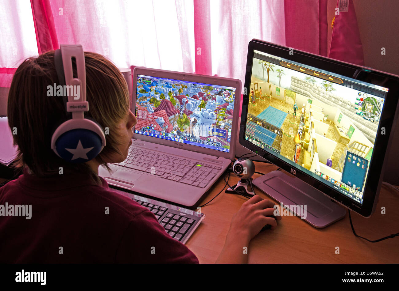 A teenage boy playing computer games on two screens Stock Photo