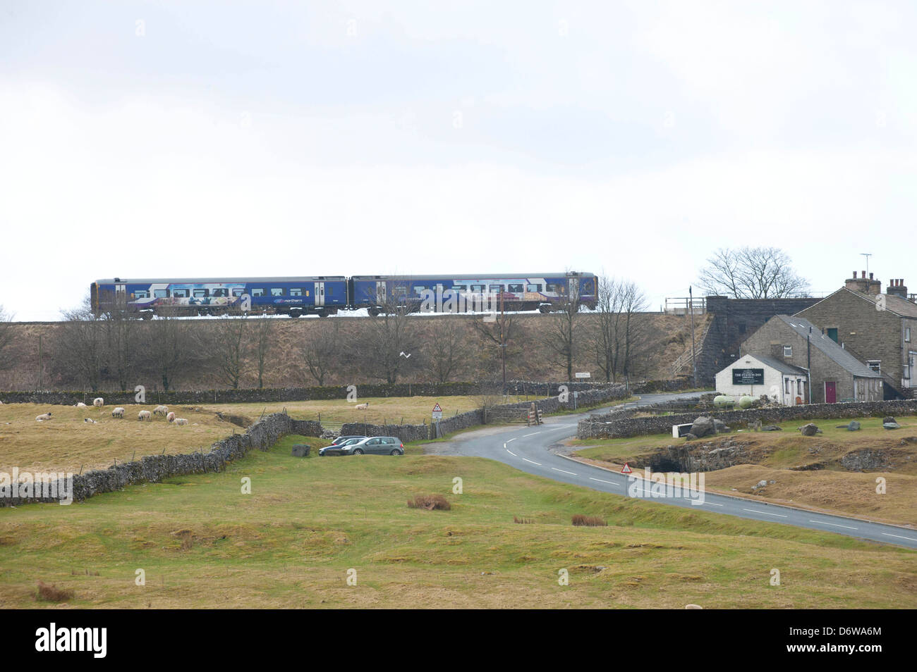 Northern rail train in West Yorkshire livery on embankment approaching Ribblehead viaduct Stock Photo