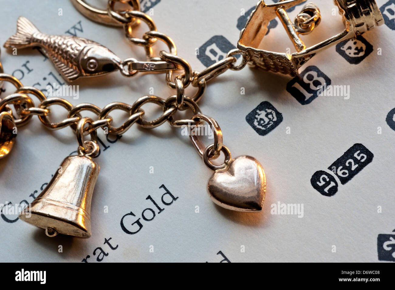 1960's gold charm bracelet on page of gold purity and hallmarks reference book Stock Photo