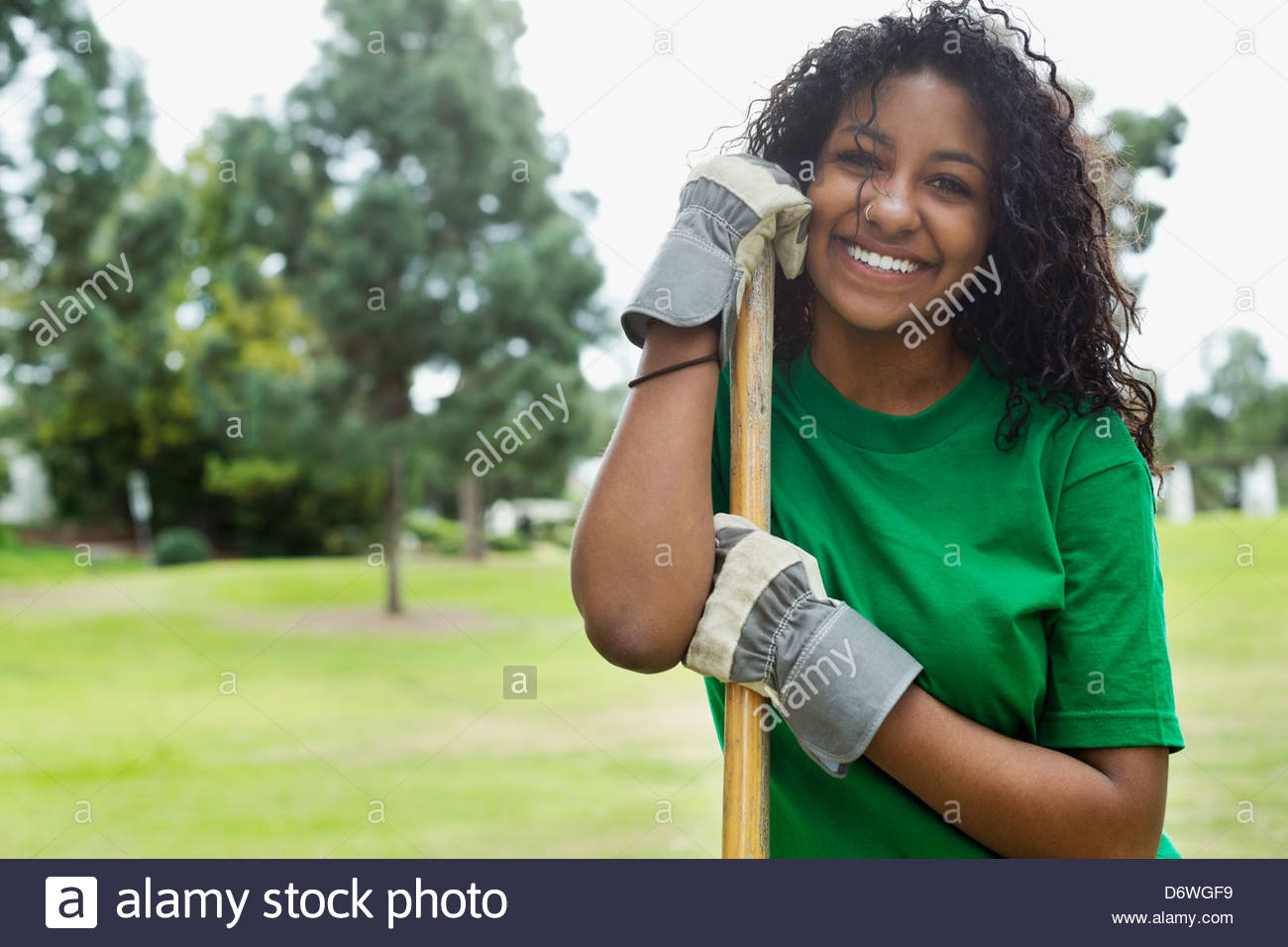 Portrait of beautiful young environmentalist holding rake in park Stock