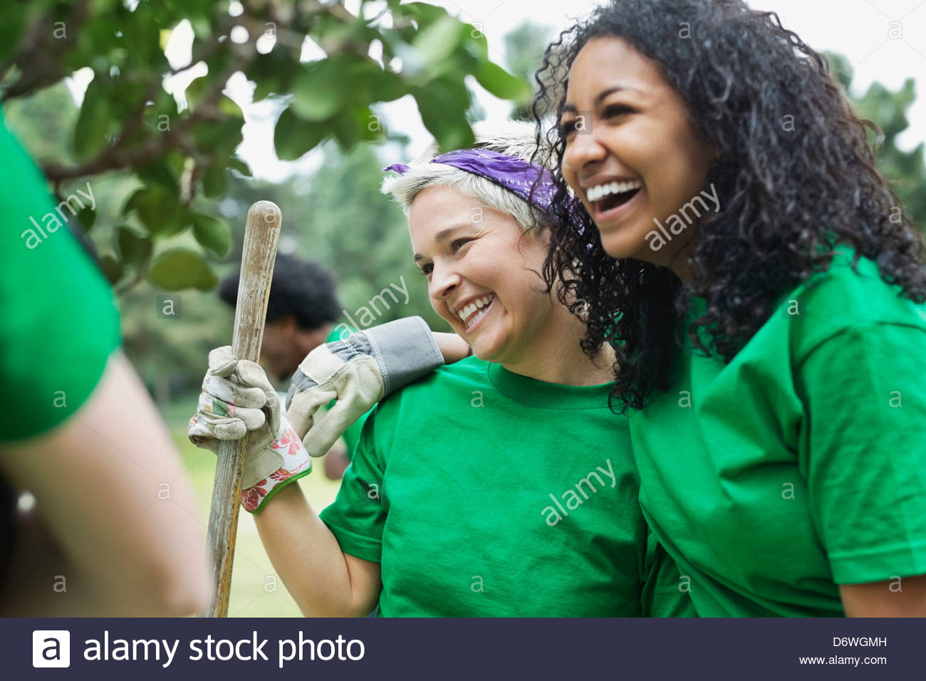 Happy young female environmentalist with friend holding shovel in park Stock Photo