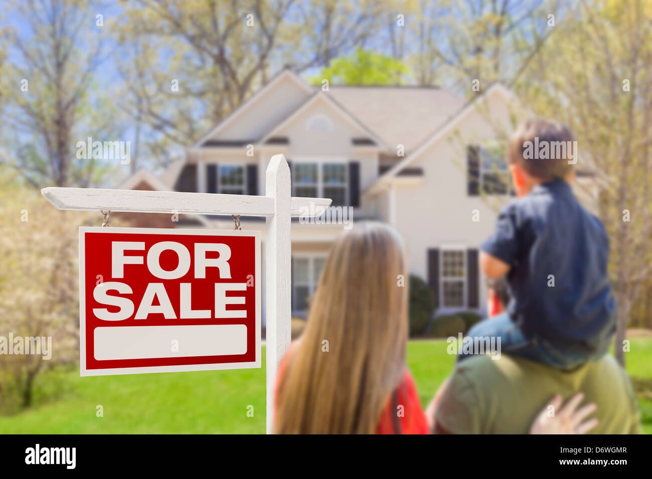 Curious Family Facing For Sale Real Estate Sign and Beautiful New House. Stock Photo