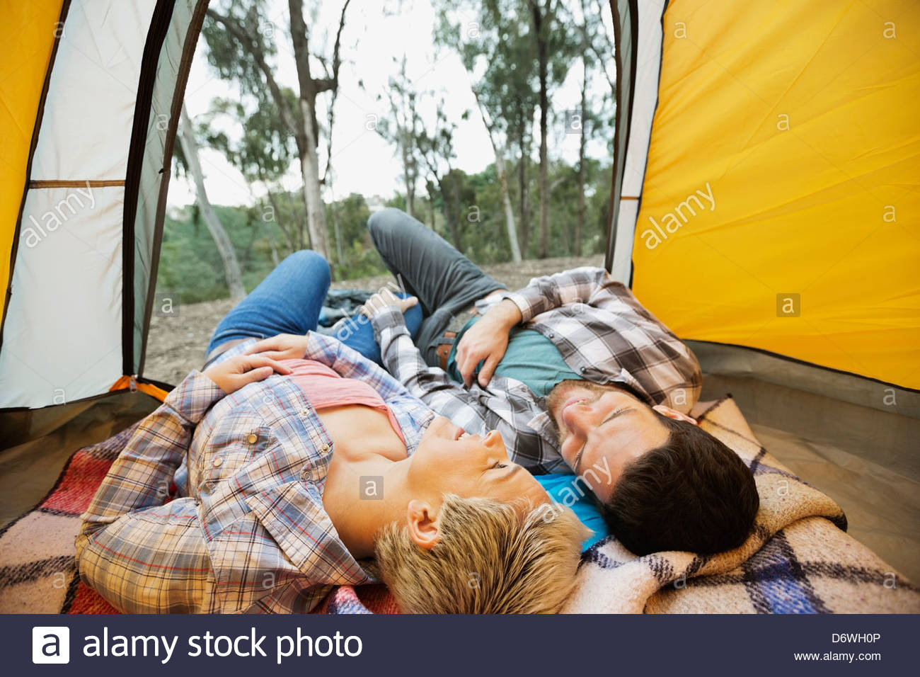 Happy couple lying down together in tent Stock Photo