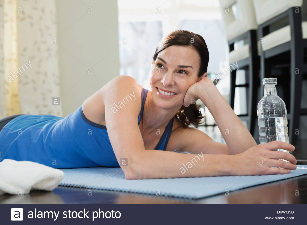 Happy mature woman resting on exercise mat Stock Photo