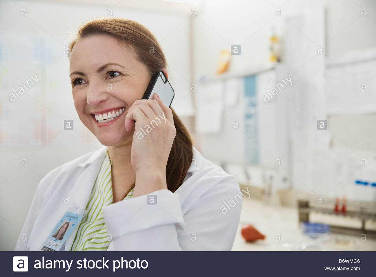 Happy mature lab technician using mobile phone in lab Stock Photo