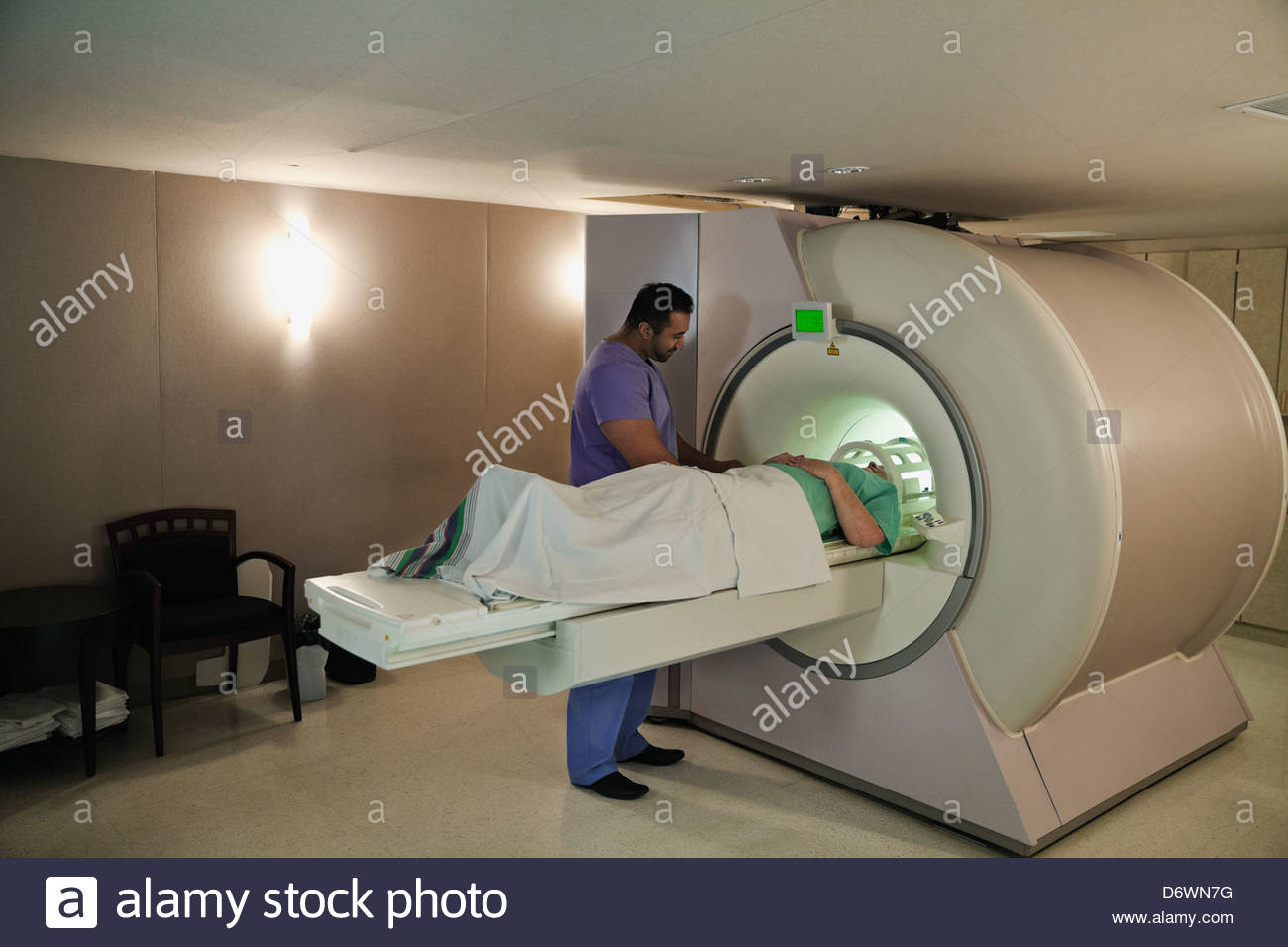 Male radiologist doing CTScan on female patient in examination room