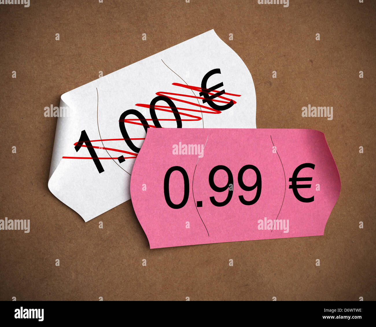 0.99 € psychological price written on a pink label upon another one where it's written 1.00 euro, brown kraft paper background Stock Photo