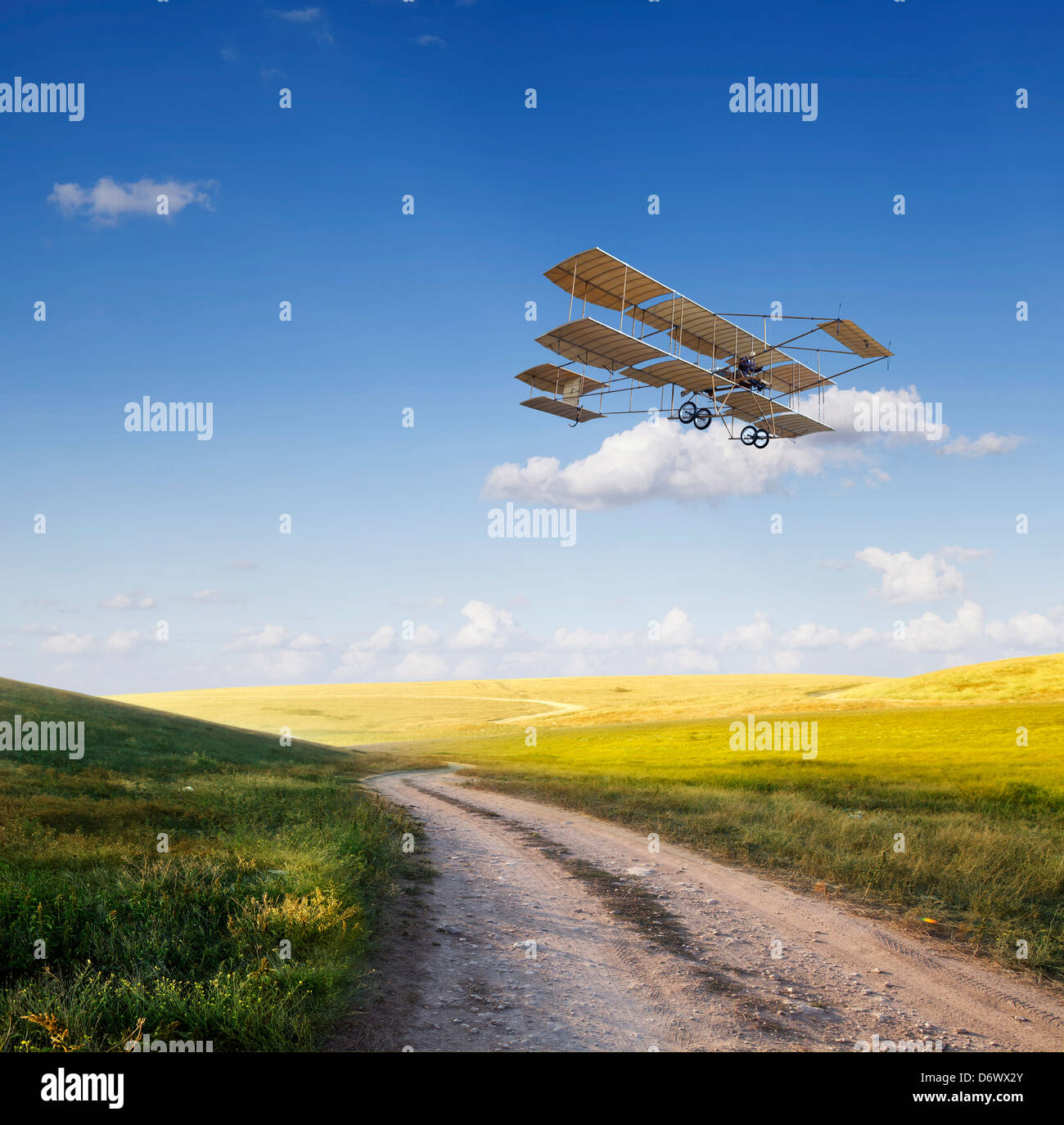 Old airplane flying above the beautiful green field Stock Photo