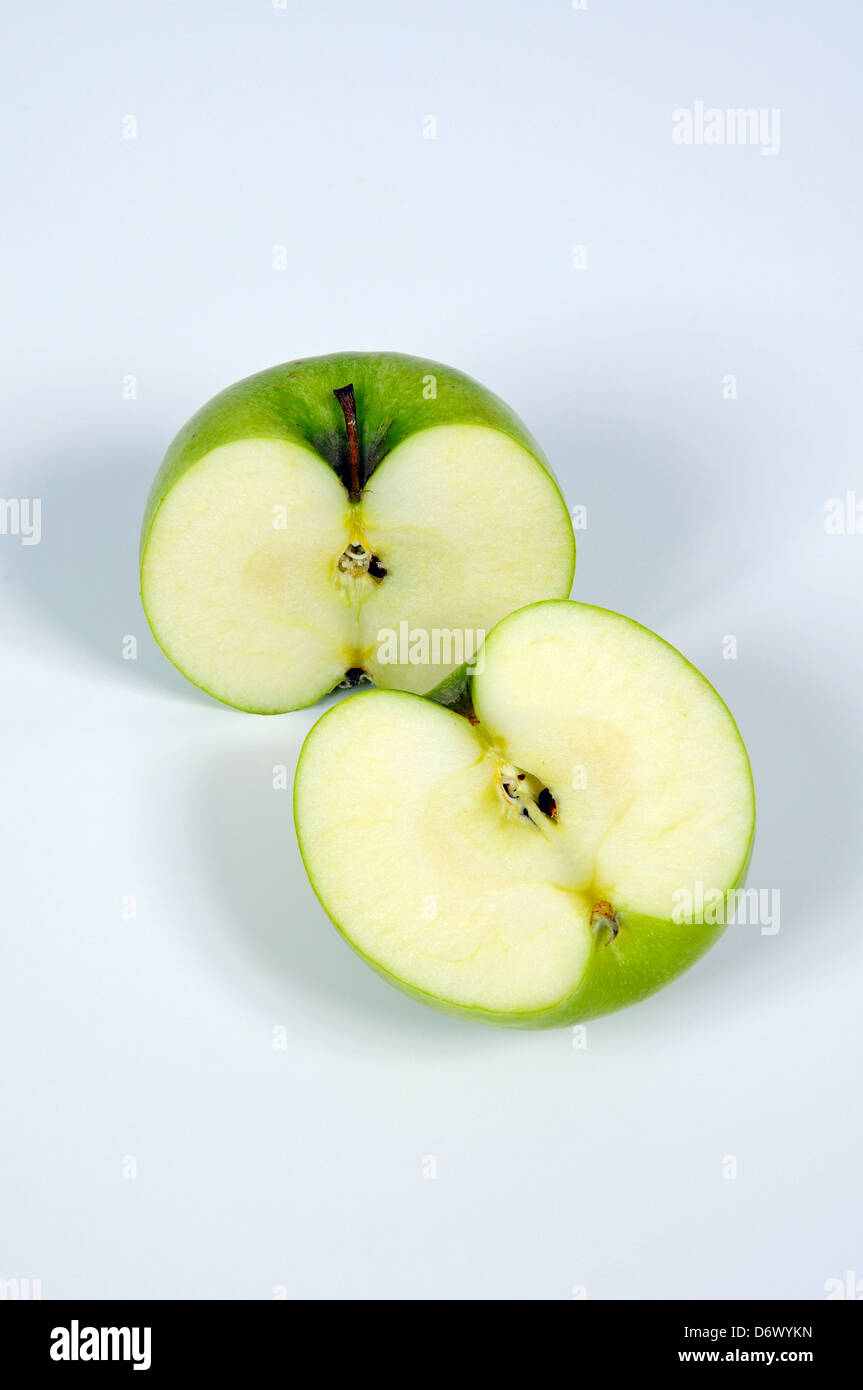 Green apple cut in half against a plain background. Stock Photo