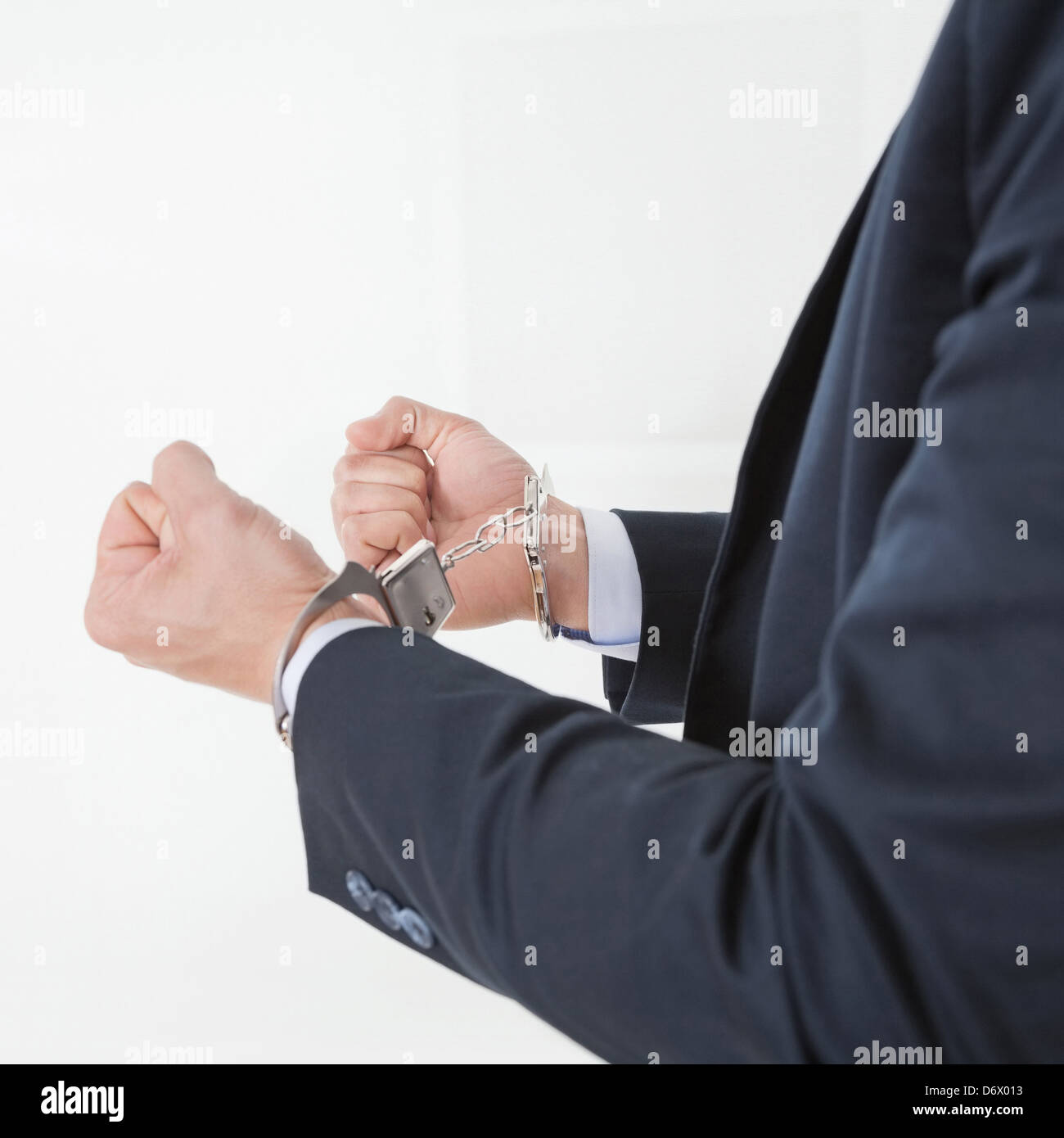 Businessman in handcuffs getting arrested for white collar crimes Stock