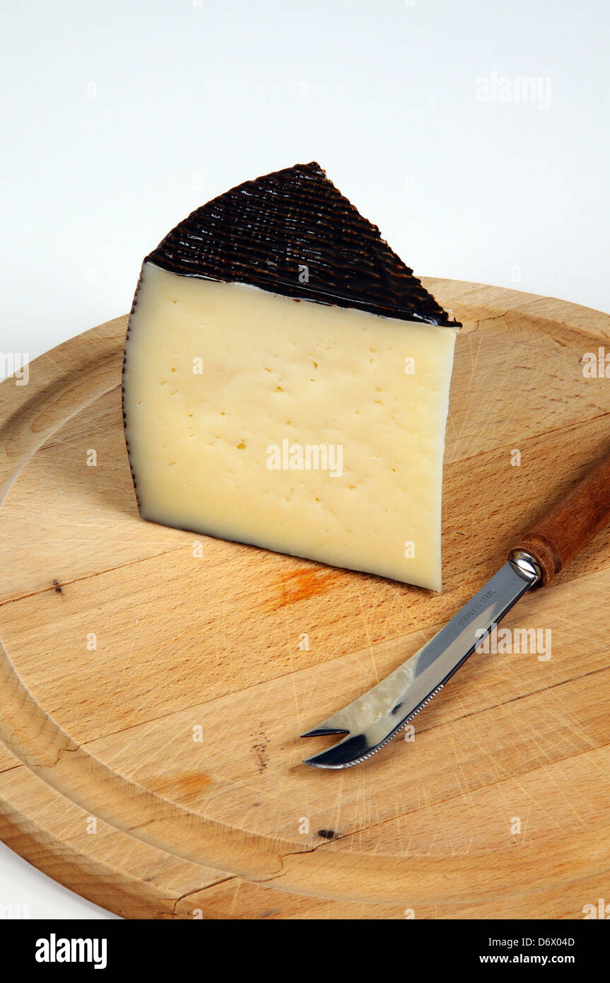 Wedge of Manchego cheese on a cutting board with a cheese knife Stock