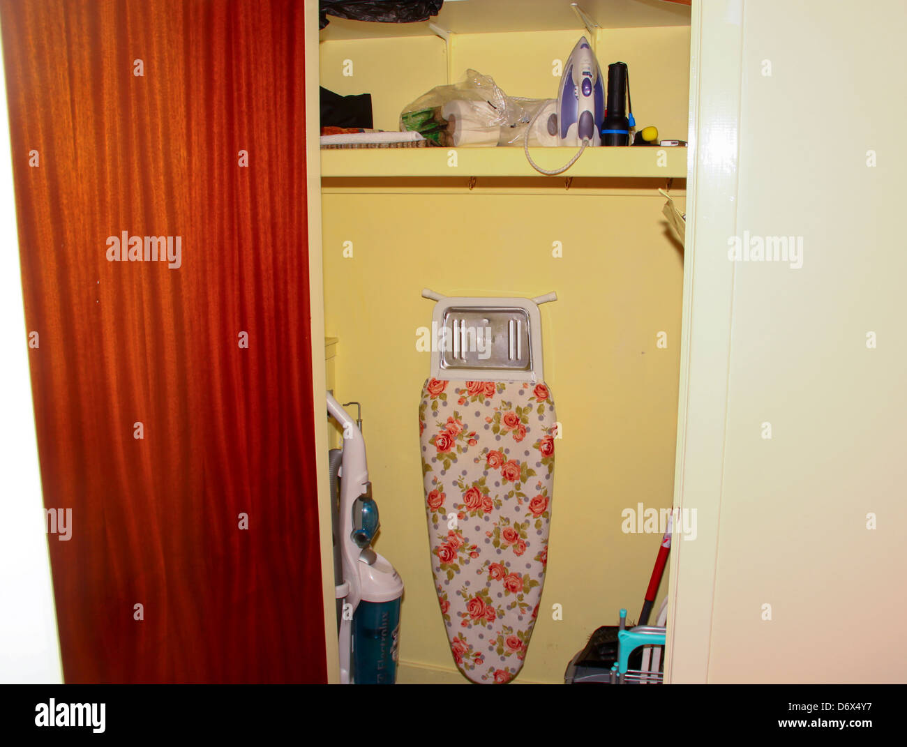 Hall utility cupboard with ironing board and vacuum cleaner Stock Photo