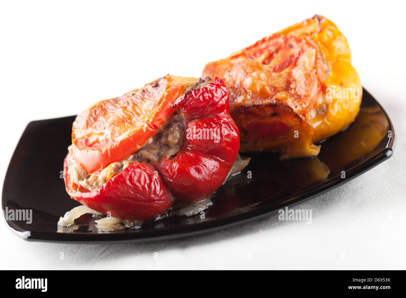Stuffed bell peppers with chopped meat, cheese and tomato on black plate Stock Photo