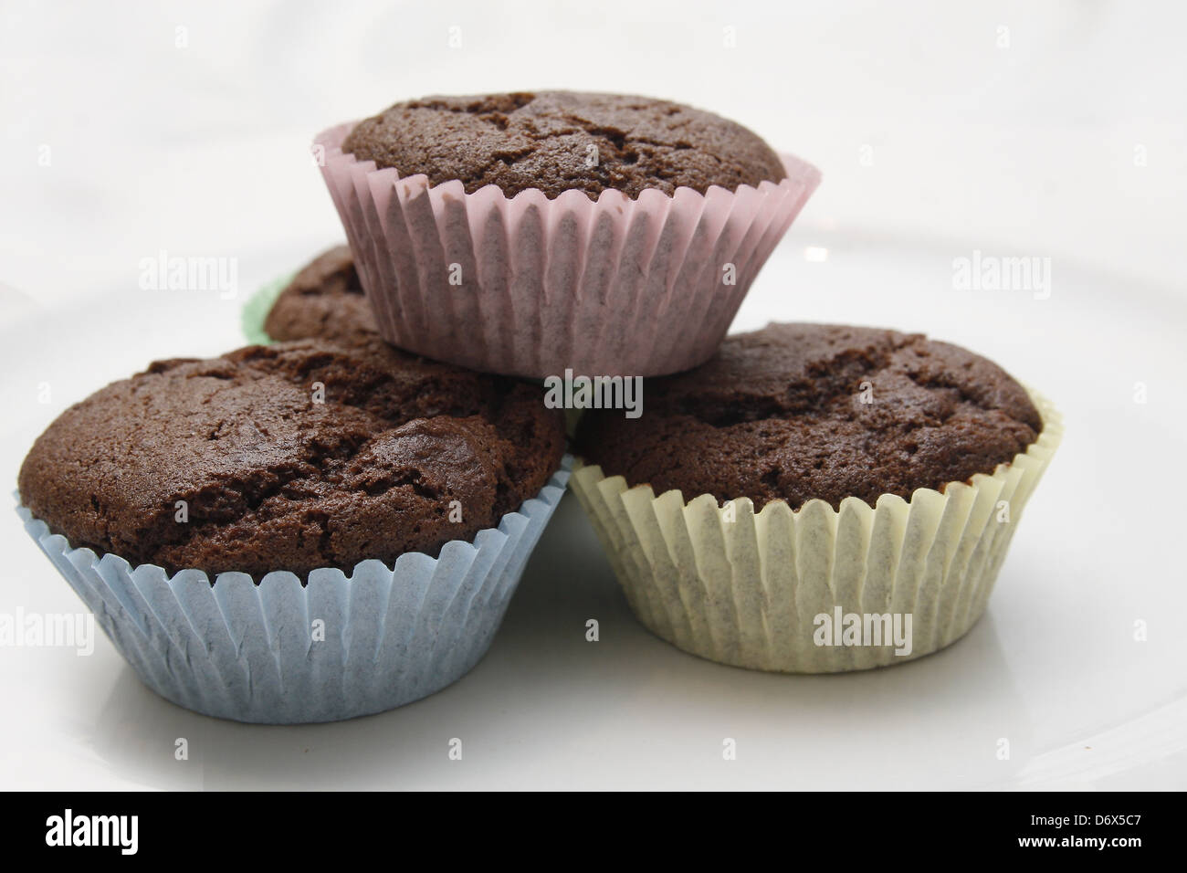 chocolate cupcakes in multicoloured bun cases on white plate Stock Photo