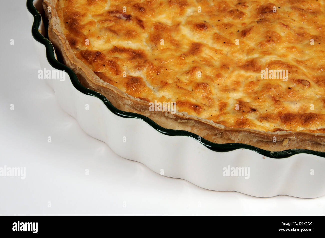 Quiche Lorraine in a fluted flan dish against a white background Stock