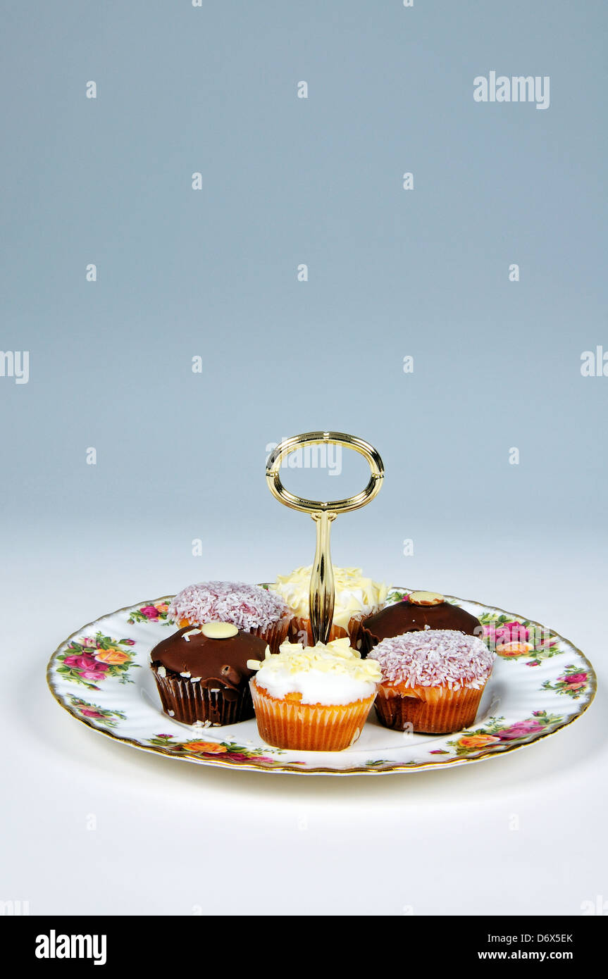 Cake plate with tea-time cake selection - Lemon drizzle cake, coconut madeleine, chocolate sponge. Stock Photo