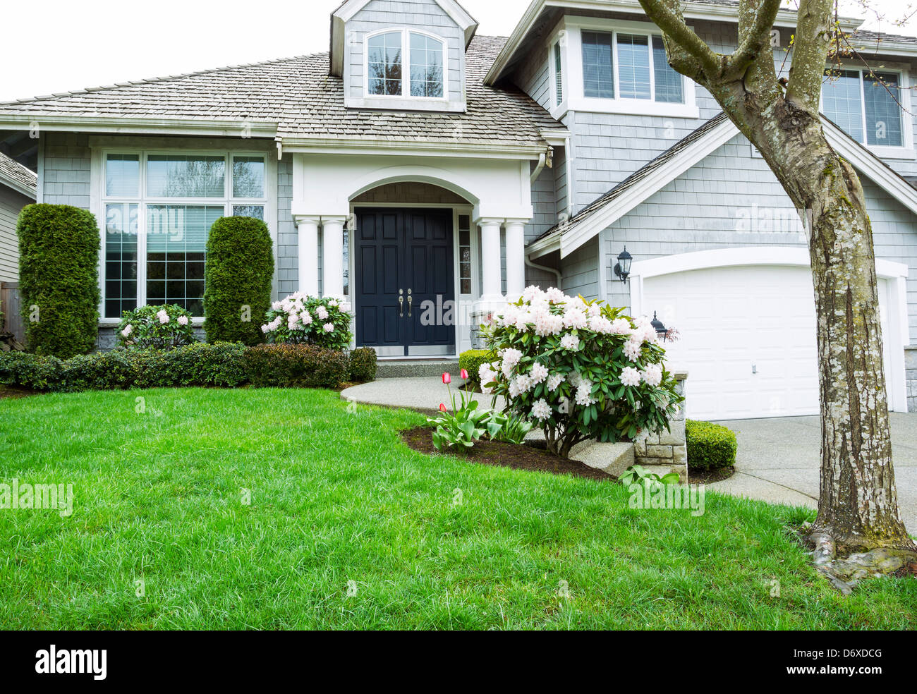 Modern home with plush green grass and blooming flowers during late spring in Northwest United States Stock Photo