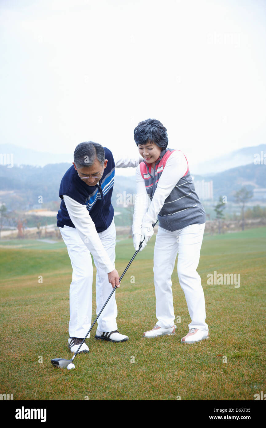 a man teaching his wife how to play golf Stock Photo