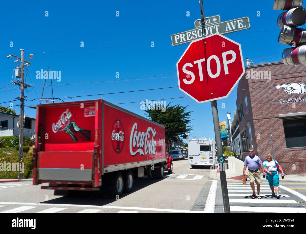 Street scene in Monterey California with obese couple carrying drink cartons and takeaway food bag, with passing Coca Cola lorry Stock Photo