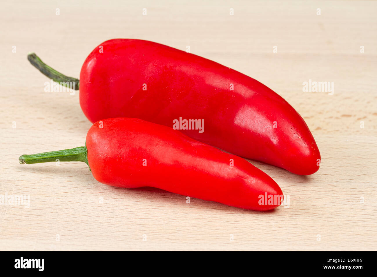 Two red chillis on wooden chopping board Stock Photo