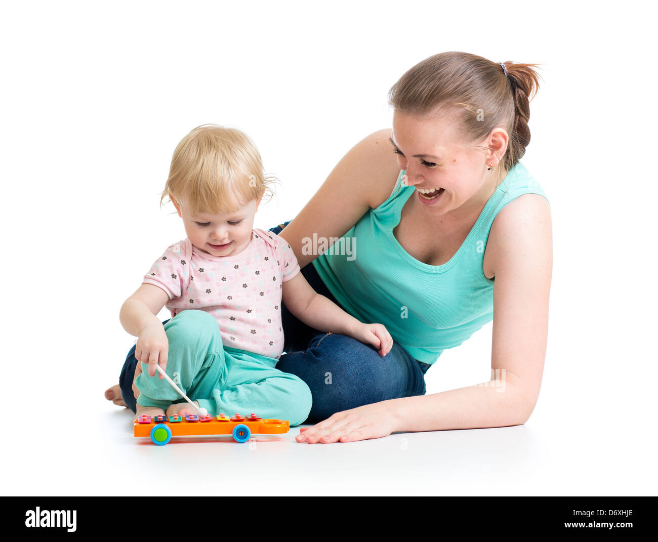Mother and baby girl having fun with musical toy. Isolated on white background Stock Photo