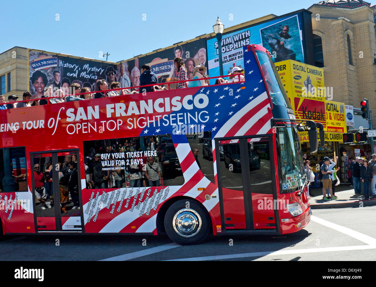 Open top red city tour bus at Fisherman's Wharf with tourists on sunny