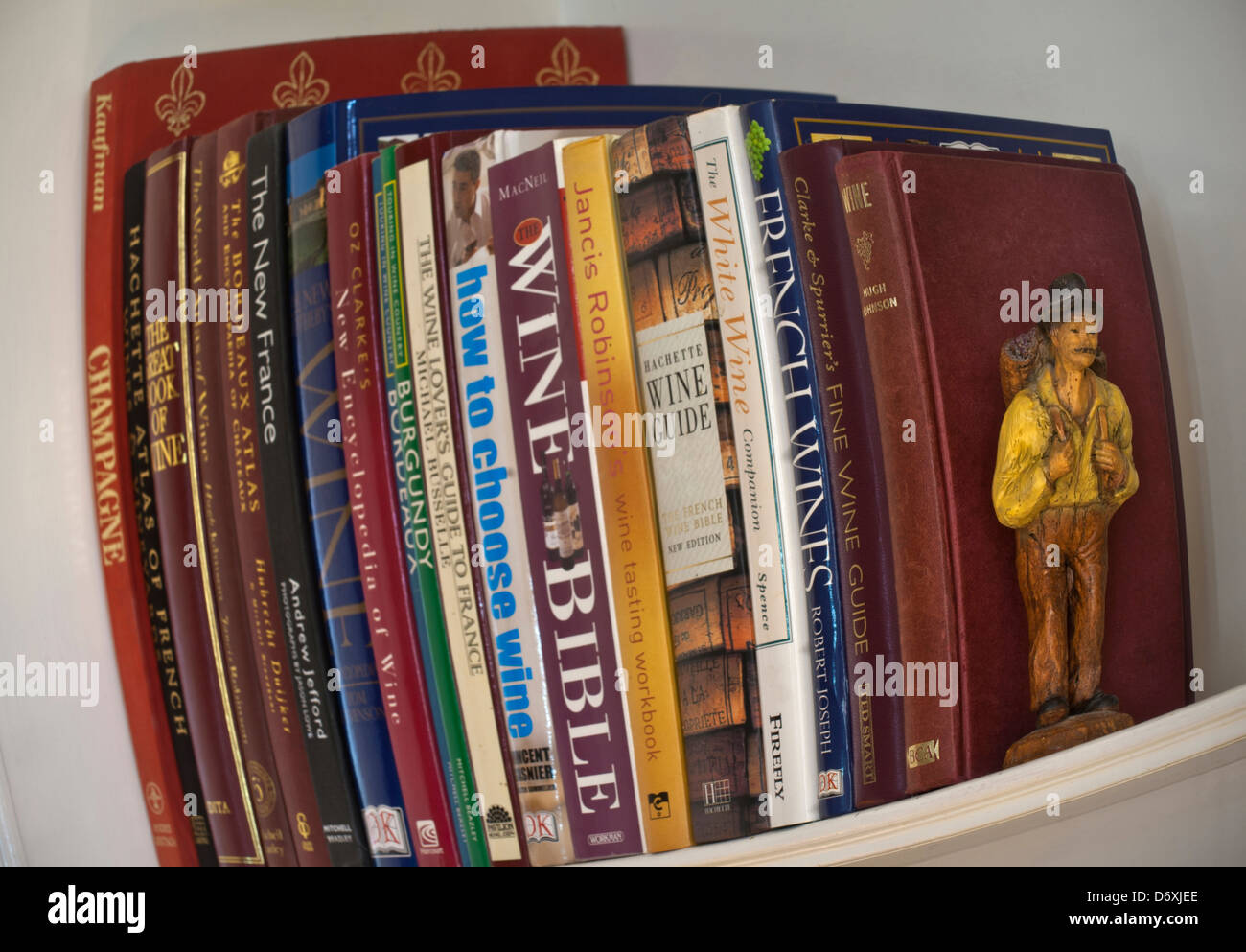 Fish eye effect image of variety classic and contemporary wine reference books on bookshelf with grape harvester bookend figure Stock Photo