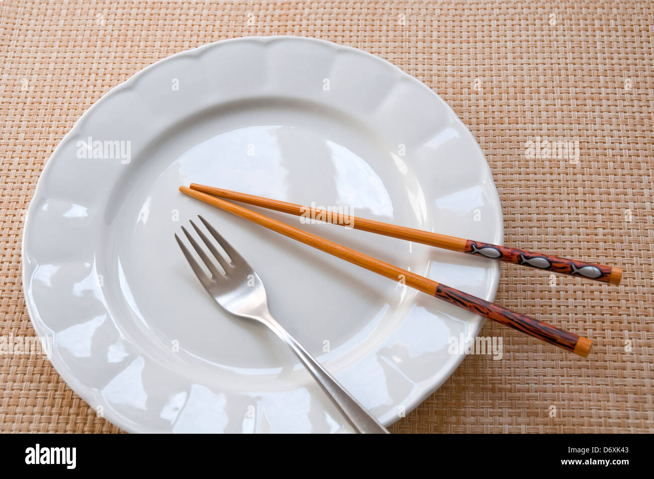 Fork and chopsticks on an empty plate. Stock Photo