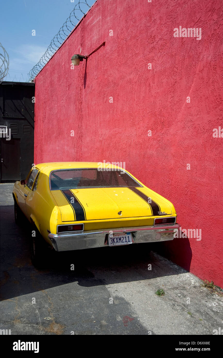 Bright yellow car parked against red wall Stock Photo