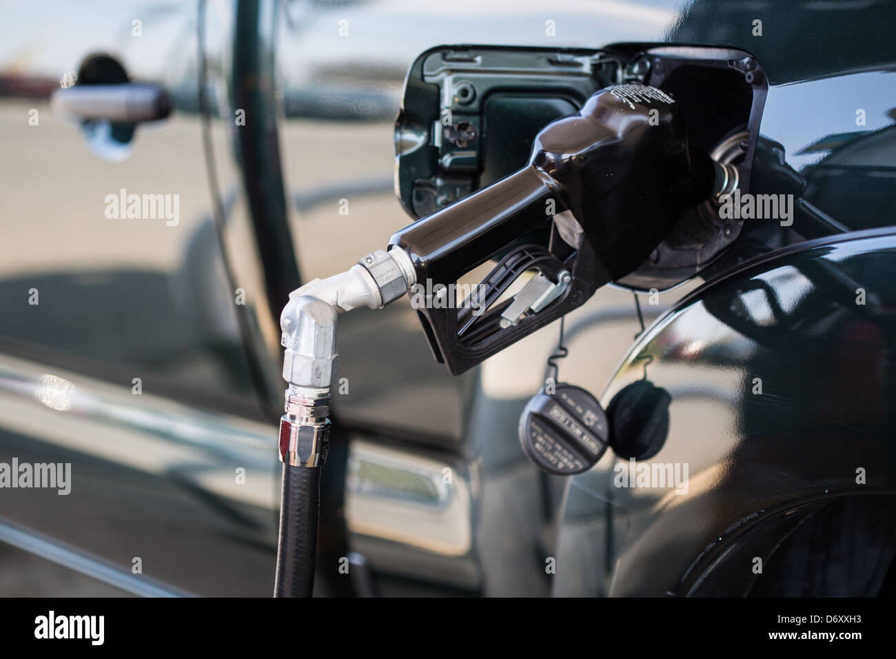 A close up of a gas pump filling up a green pickup truck. Fuel consumption. Stock Photo
