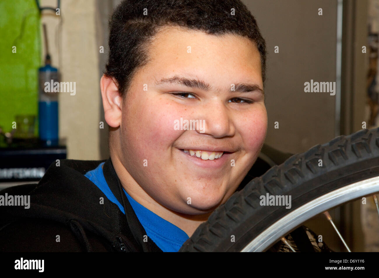 Happy teen repairing bicycle in the nonprofit Express Bike Shop. St