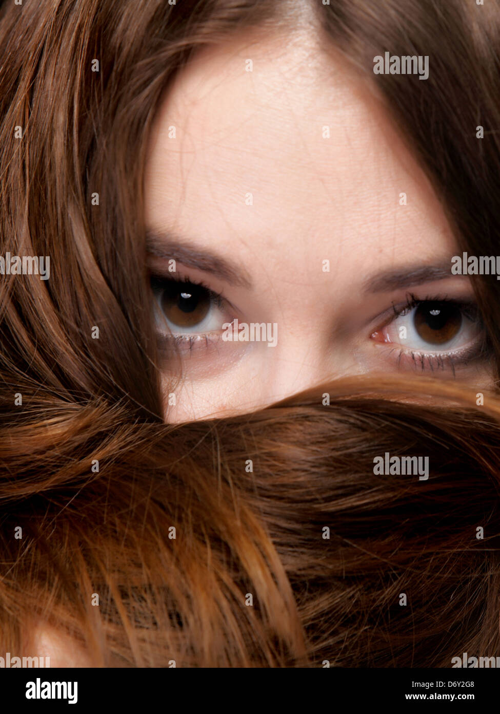 Close-up portrait of a beautiful woman covers the face by long brown hairs Stock Photo