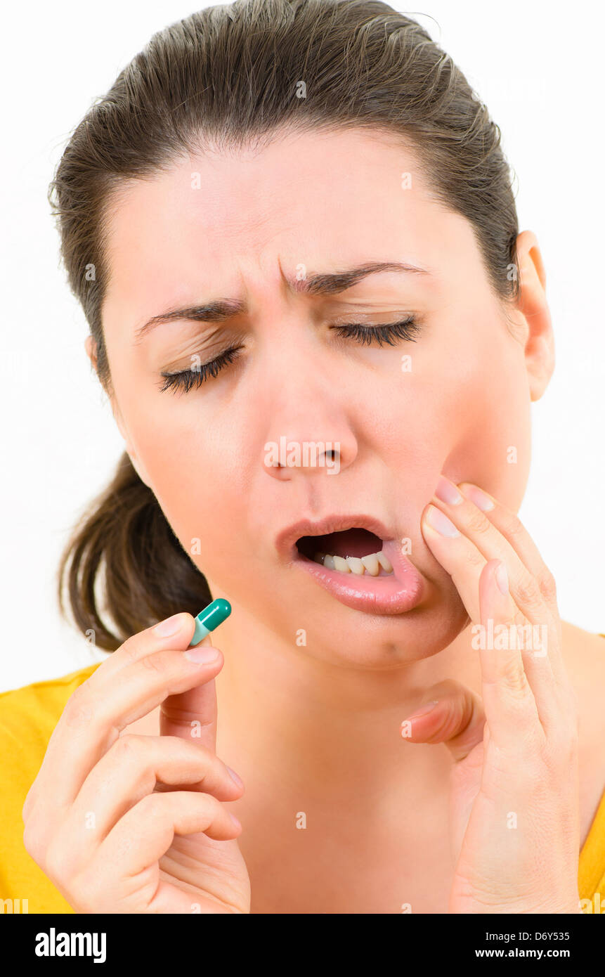 Scared woman with toothache holding a pill Stock Photo