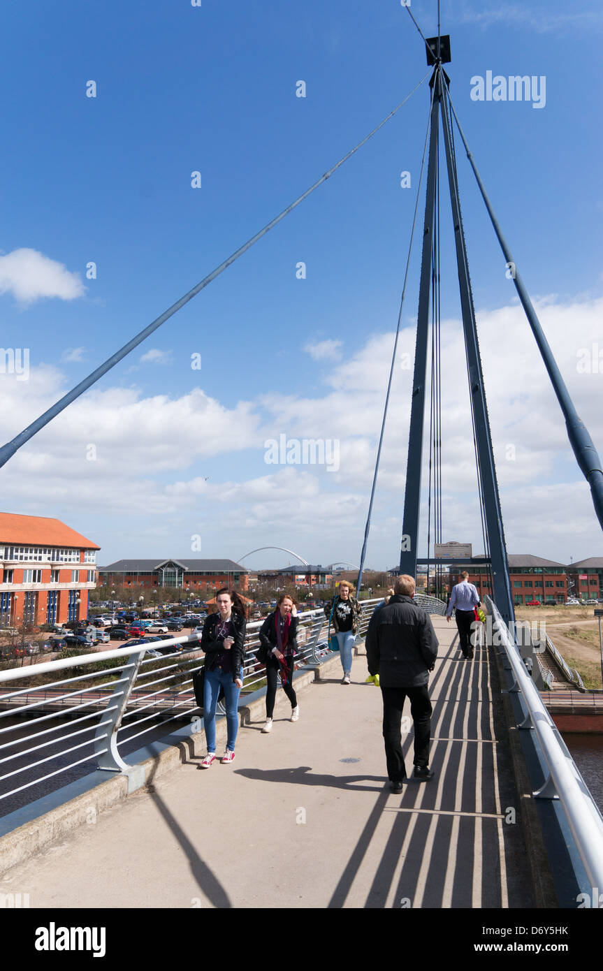 Group of people walking across the MIllennium footbridge Stockton-on-Tees north east England UK Stock Photo