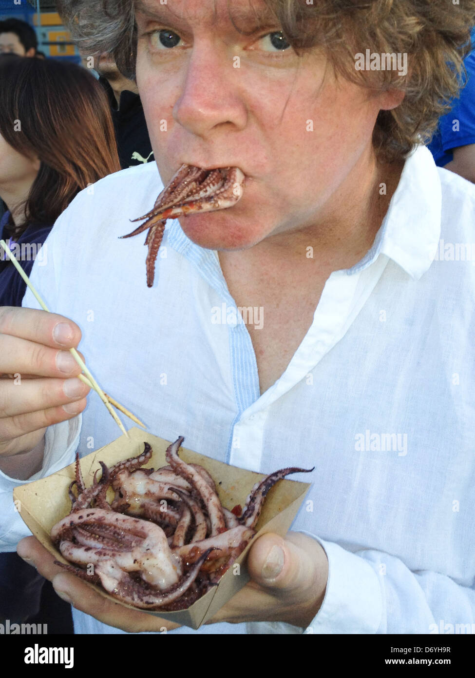 Caucasian man eating squid Stock Photo - Alamy