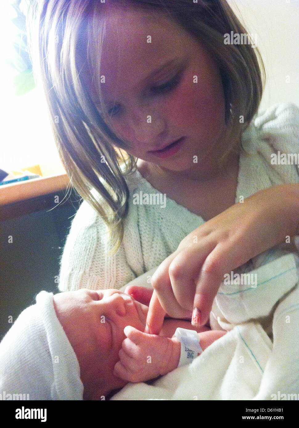 Caucasian girl looking at newborn baby - Smartphone Captured Stock Image