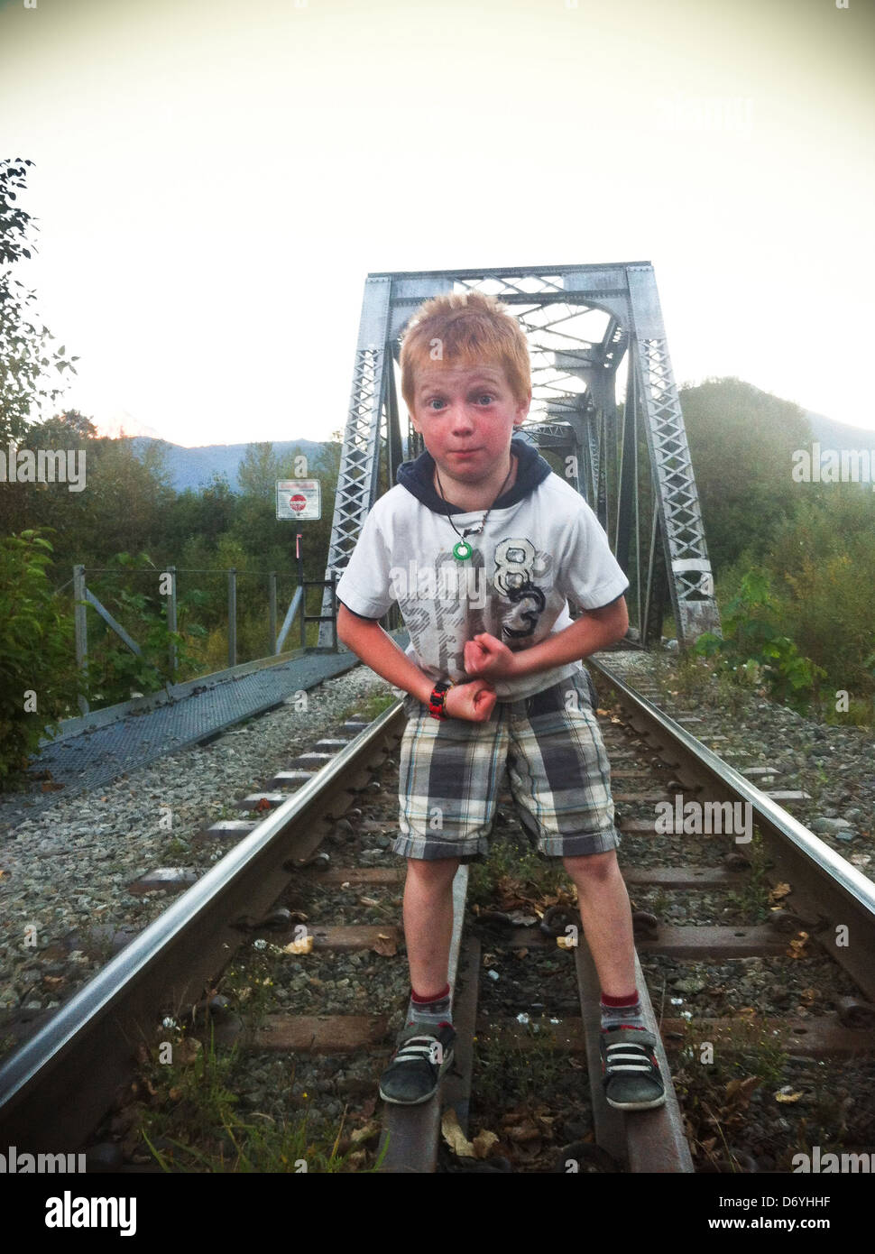 Caucasian boy standing on railroad tracks - Smartphone Captured Stock Image
