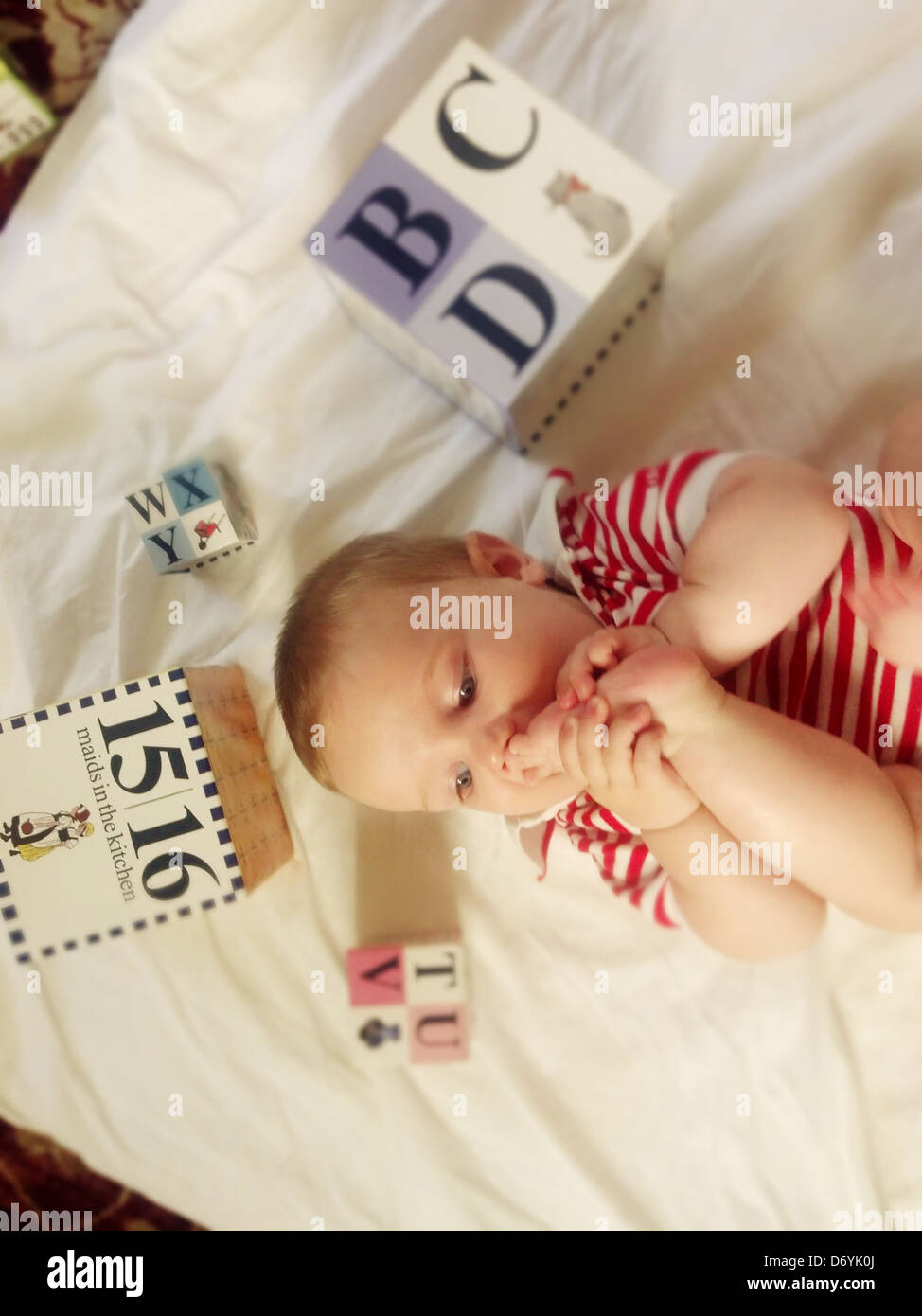 Caucasian baby biting foot - Smartphone Captured Stock Image