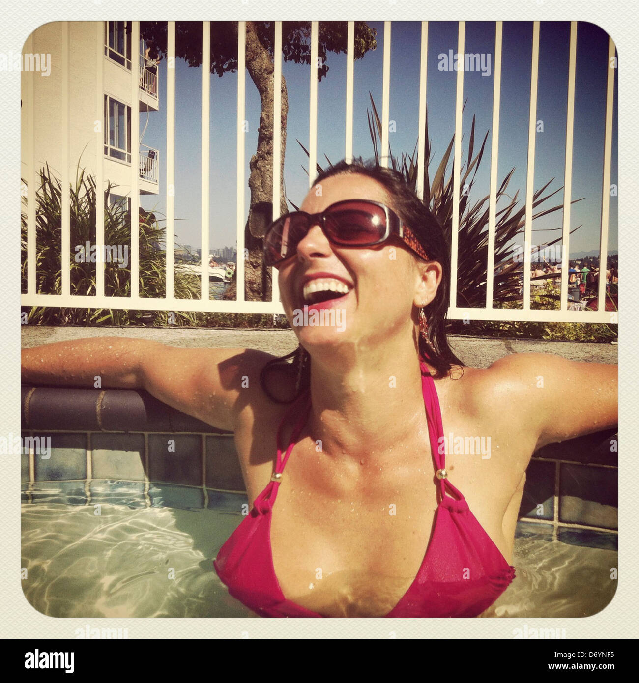 Caucasian woman laughing in swimming pool - Smartphone Captured Stock Image